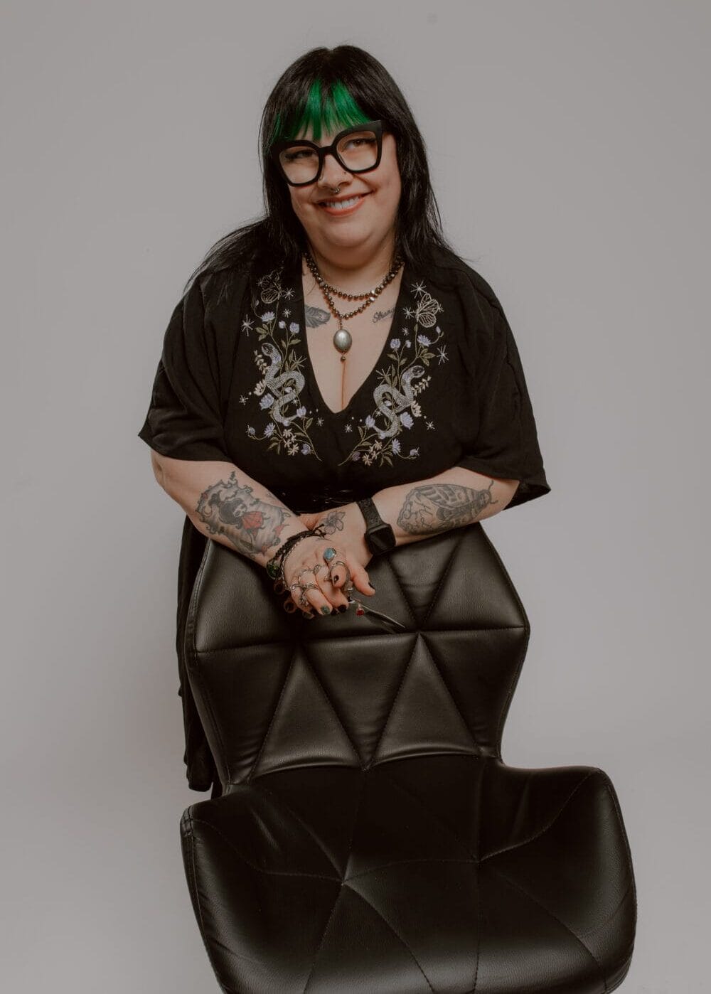 Smiling stylist with green hair streaks and tattoos at YOLOve beauty salon chair in Dartmouth Nova Scotia